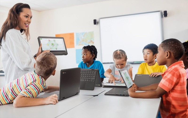 Teacher holding a Lenovo device while teaching a class