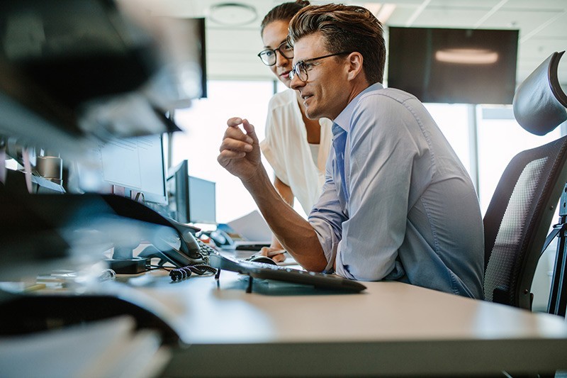 Business man sitting at desk looking at monitor